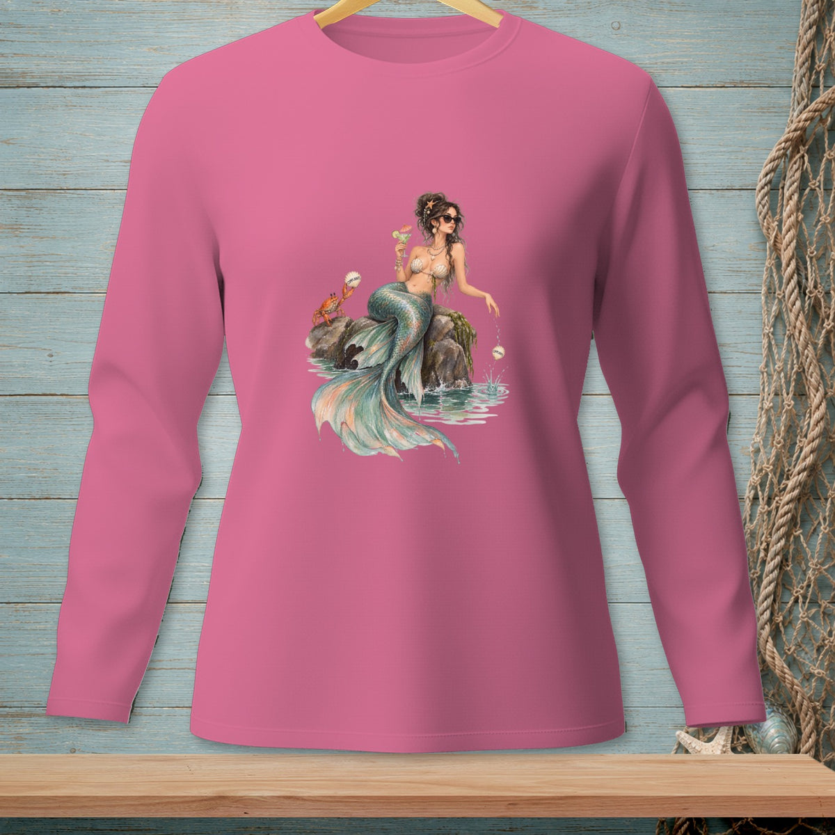Pink long-sleeve shirt with a mermaid graphic holding a drink and a crab.
