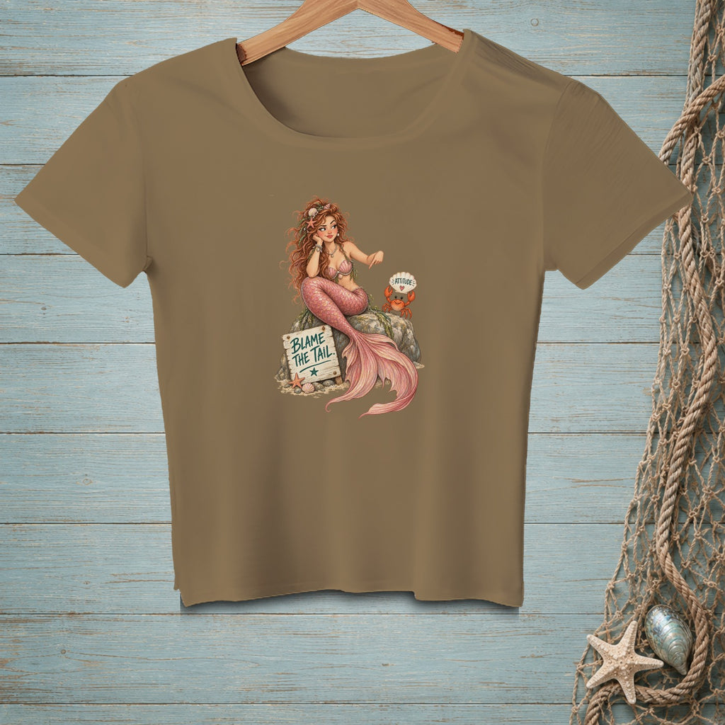 Brown t-shirt with illustration of a mermaid sitting on a rock with a sign that reads "BLAME THE TAIL."