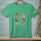 Two mermaids, one with dark hair and one with blonde, sit on rocks in the ocean.