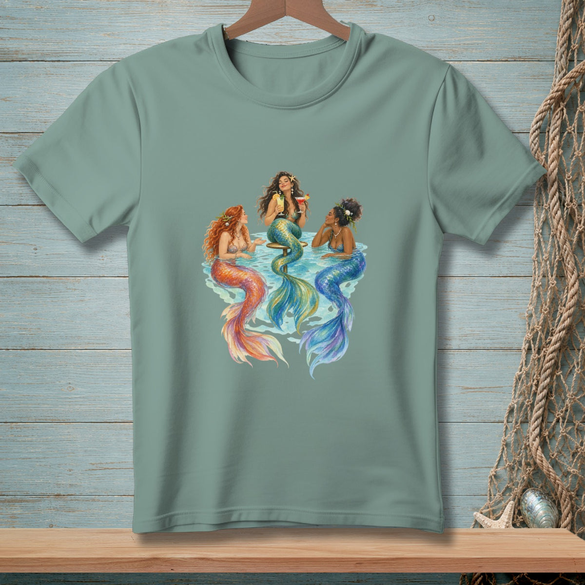 Three mermaids with colorful tails lounge in water, holding drinks.