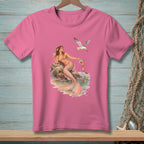 Pink t-shirt with watercolor graphic of a mermaid and a seagull near a rocky shore.