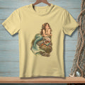Yellow t-shirt with a mermaid lounging on rocks, holding shells and sea treasures.