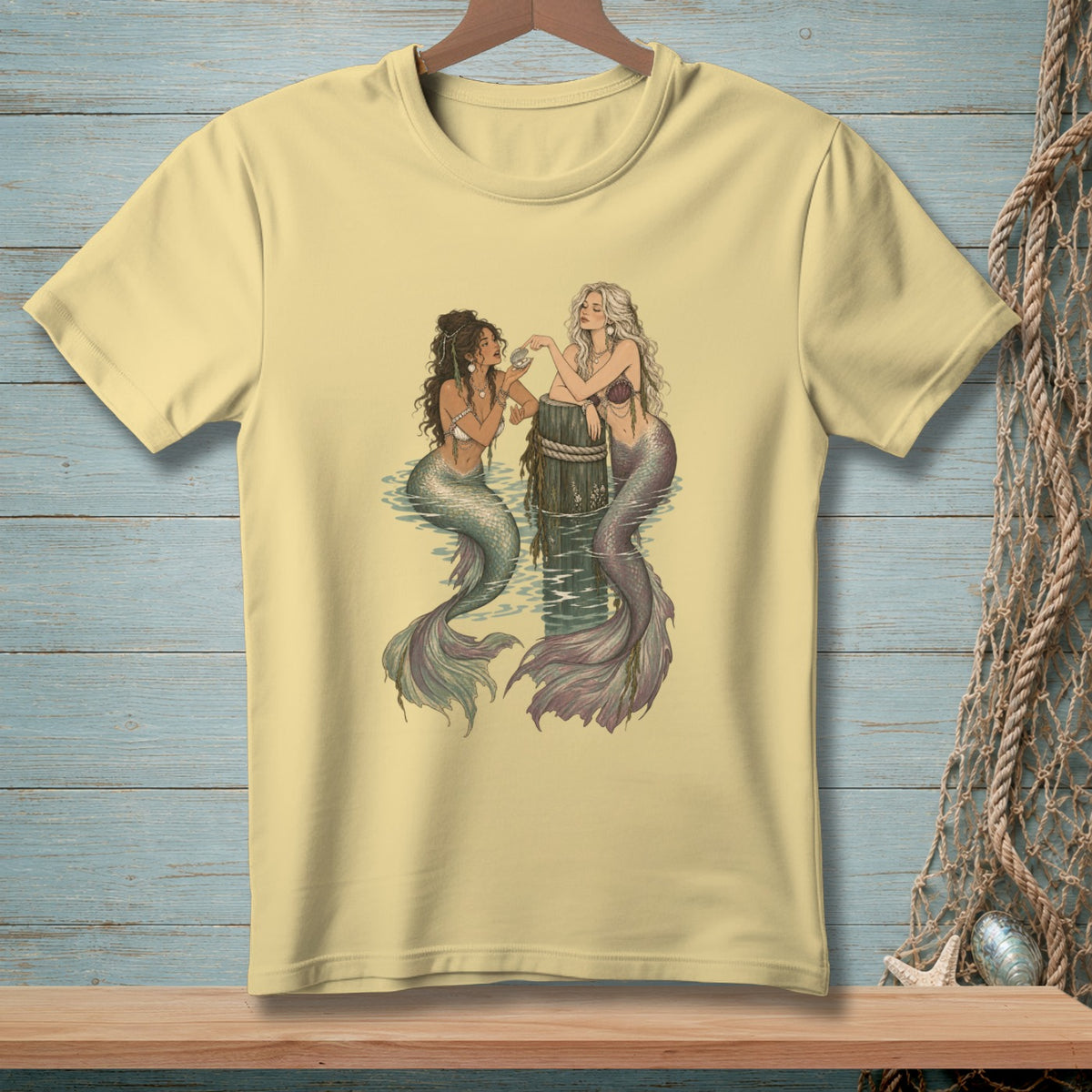 Two mermaids sitting by a wooden post in the water, one holding a shell.