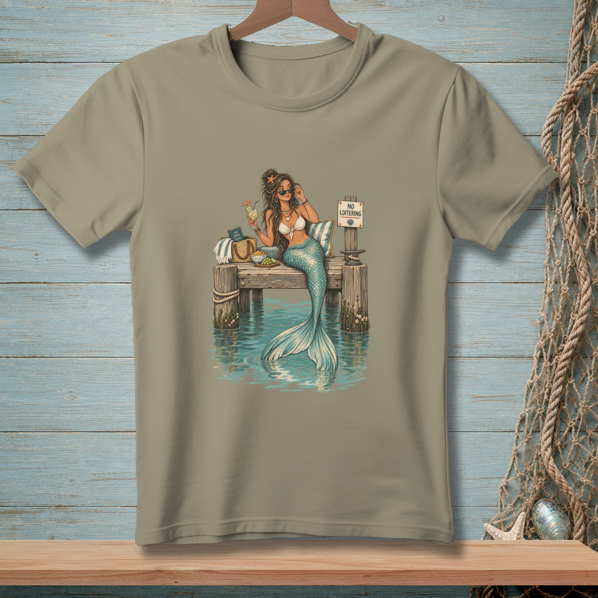 Mermaid with sunglasses and drink on pier with "No Loitering" sign.