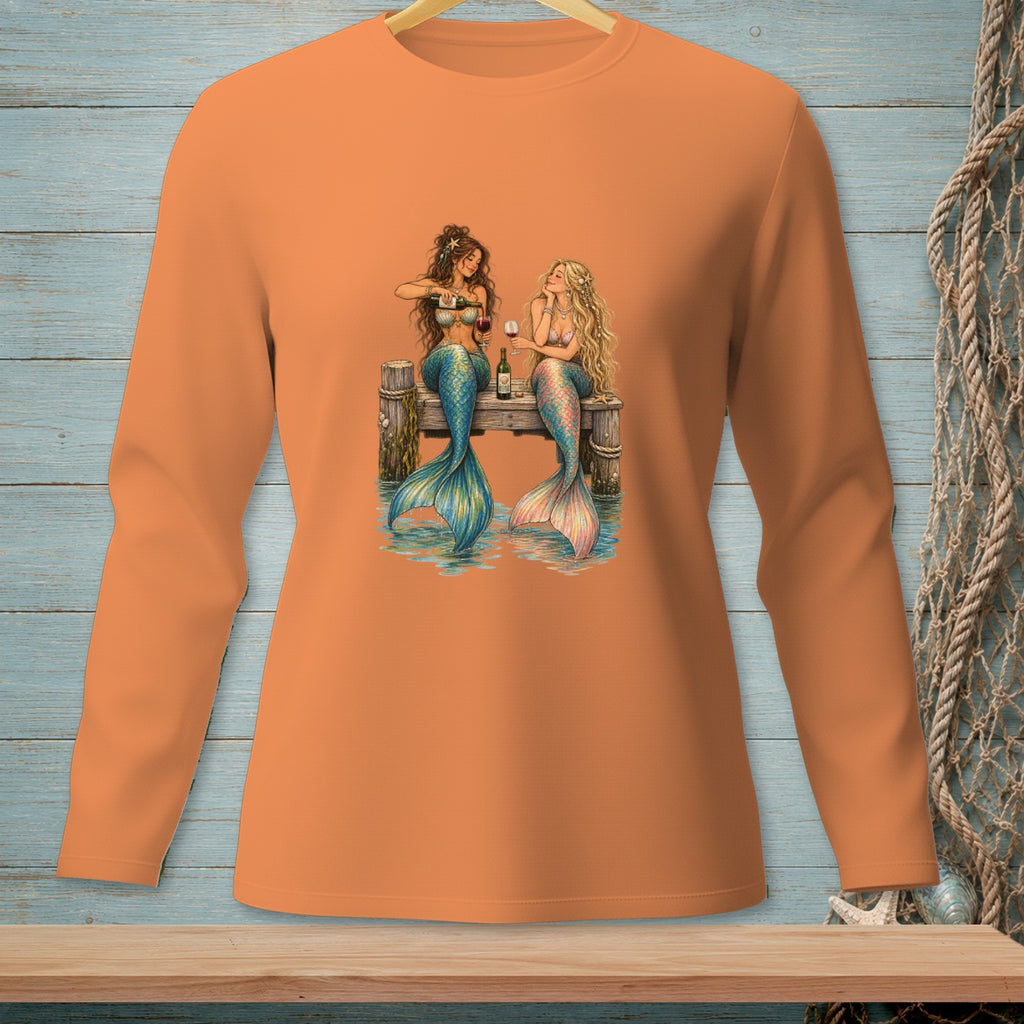 Two mermaids sitting on a dock, one pouring wine, with a bottle and glasses.