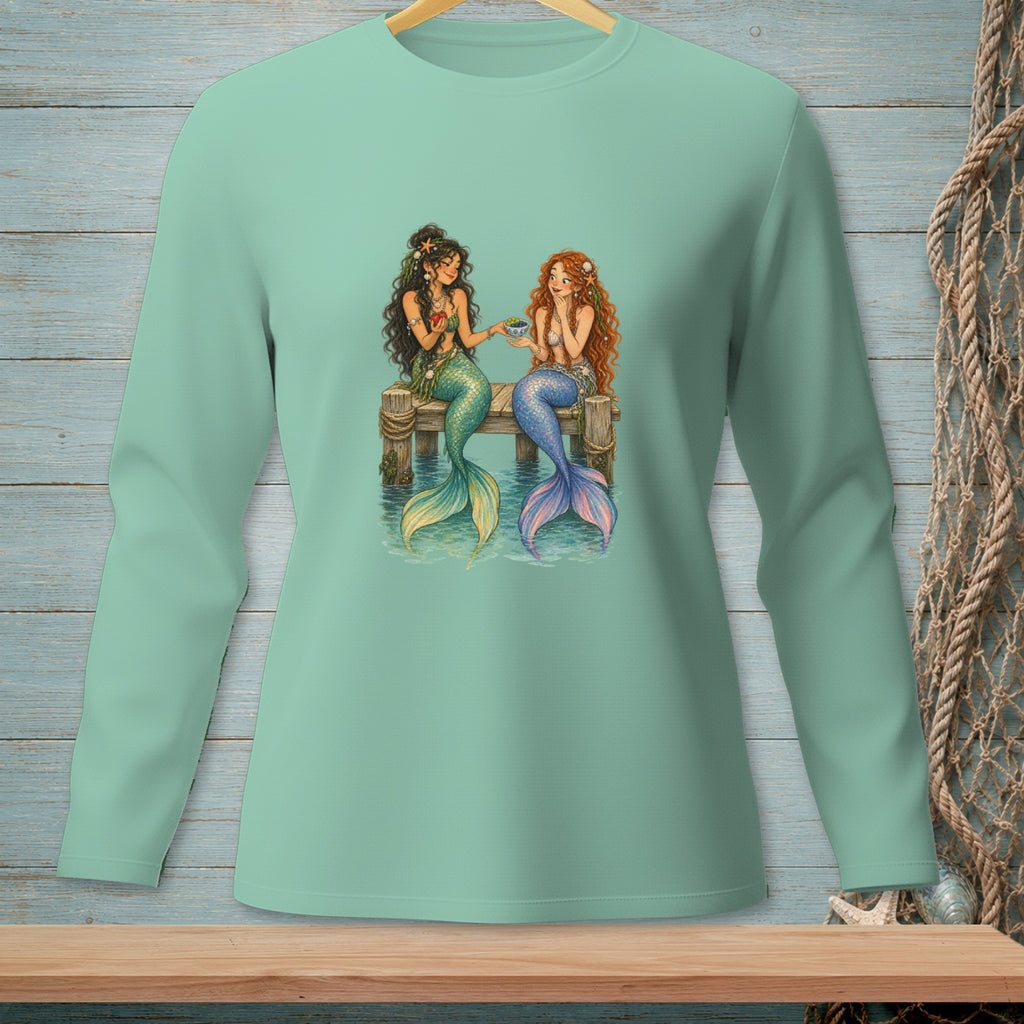 Two mermaids with colorful tails sit on a dock, one offering a seashell.