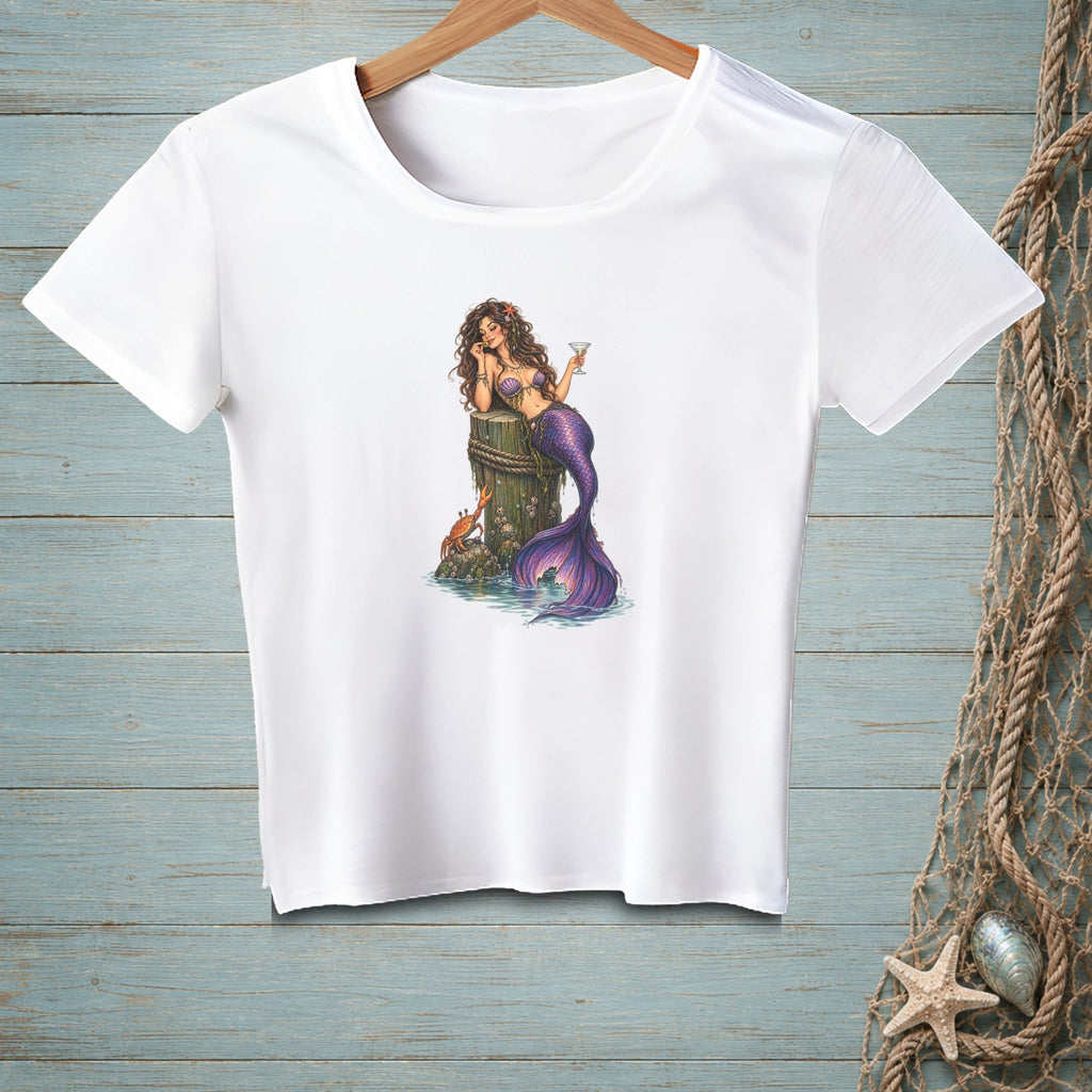 White t-shirt with a mermaid sitting on a wooden post with a crab.