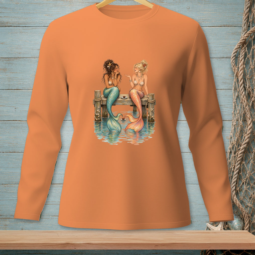 Two mermaids with colorful tails talk on a dock over water.