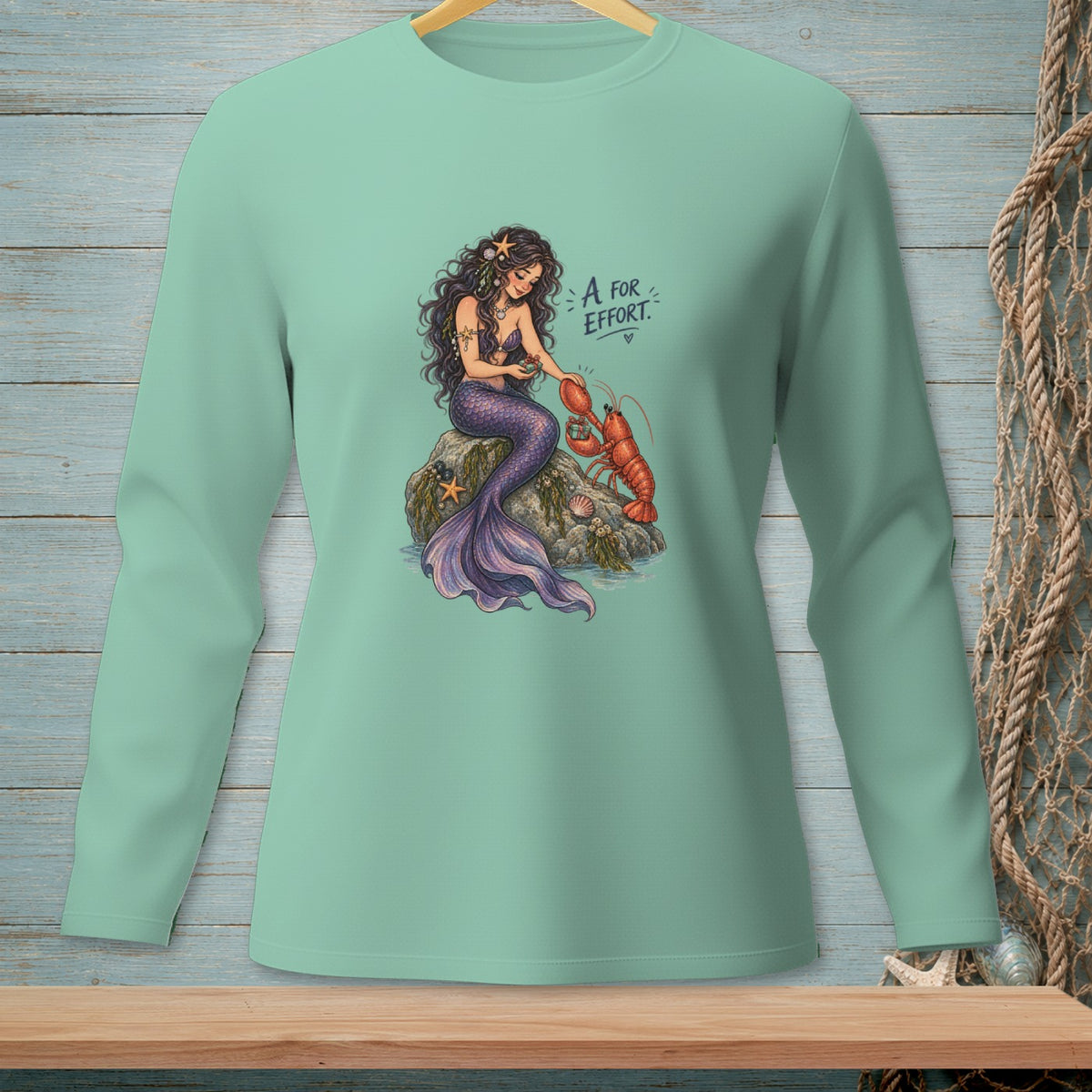 Mermaid petting a lobster with text "A for EFFORT" on light green shirt.