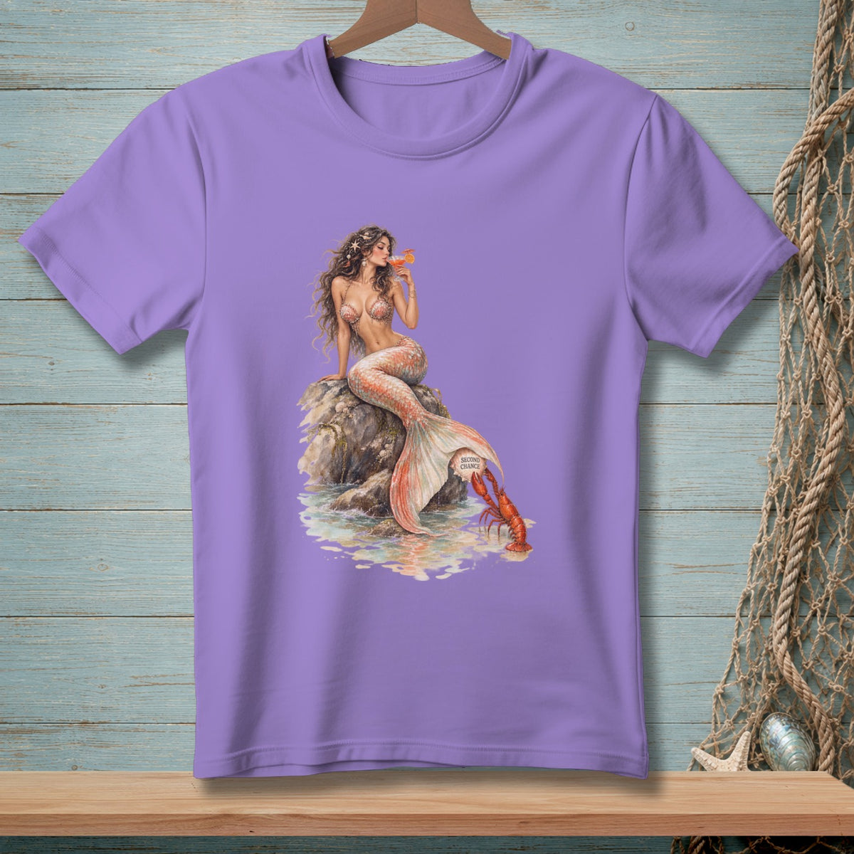 Lavender t-shirt with a mermaid holding a drink, perched on a rock next to a lobster.