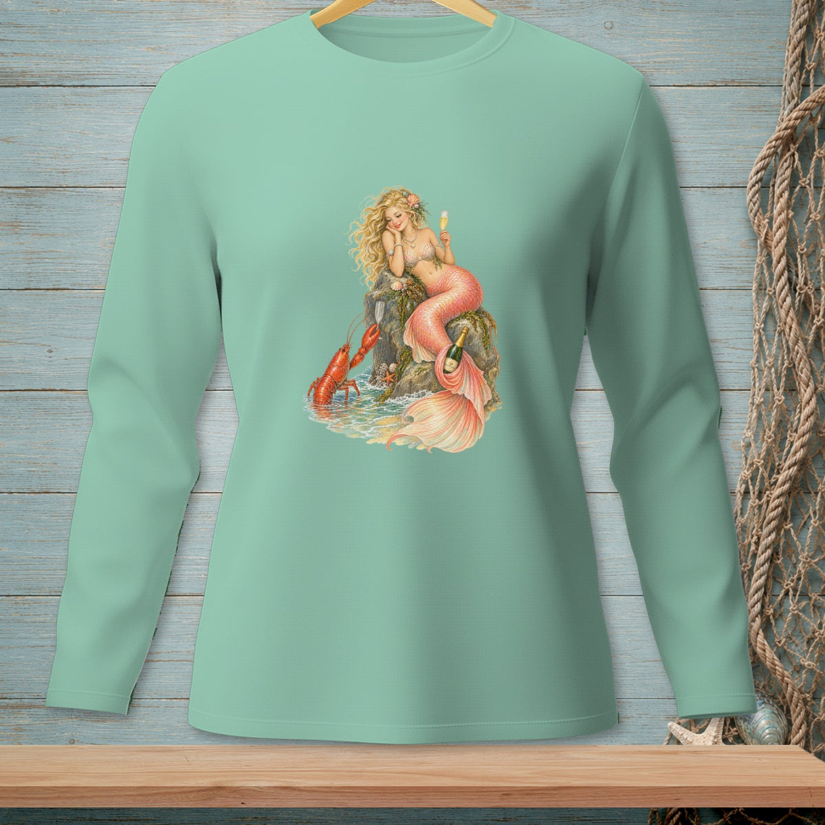 Mermaid with lobster and champagne by the sea, printed on a mint green long-sleeve shirt.