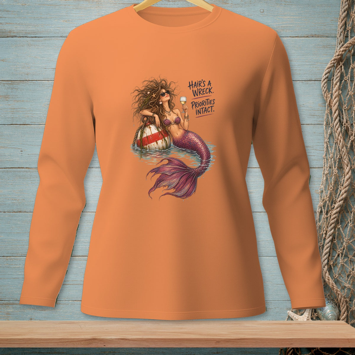 Orange long sleeve shirt with a mermaid graphic and text.