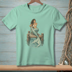 Light blue t-shirt featuring a drawing of a mermaid sitting on a dock.