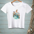 White t-shirt with a mermaid sitting on a dock, her tail in the water.