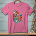 Mermaid and octopus on a dock with signpost, boat, and seagull graphic on pink t-shirt.