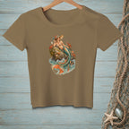 Brown t-shirt with a graphic of a mermaid lounging on a rock with crabs and waves.