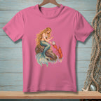 Pink t-shirt with a mermaid sitting on a rock, holding a pearl with a lobster nearby.