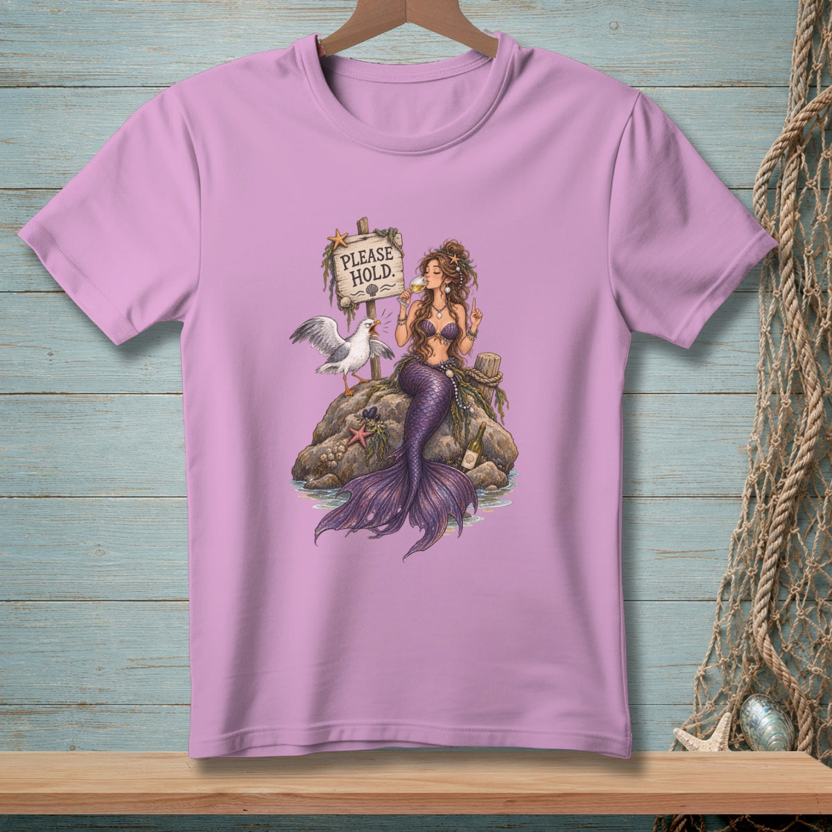 Purple t-shirt with illustration of a mermaid holding wine, a seagull, and a sign that reads "PLEASE HOLD."