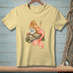 Pale yellow t-shirt with a blonde mermaid holding a cocktail, sitting on a rock with text.
