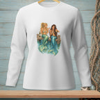 Two mermaids with blue tails sit on a dock, drinking from glasses.
