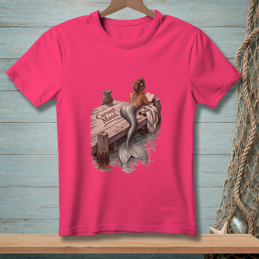 Pink t-shirt with mermaid reading on dock, text "Current Mood."
