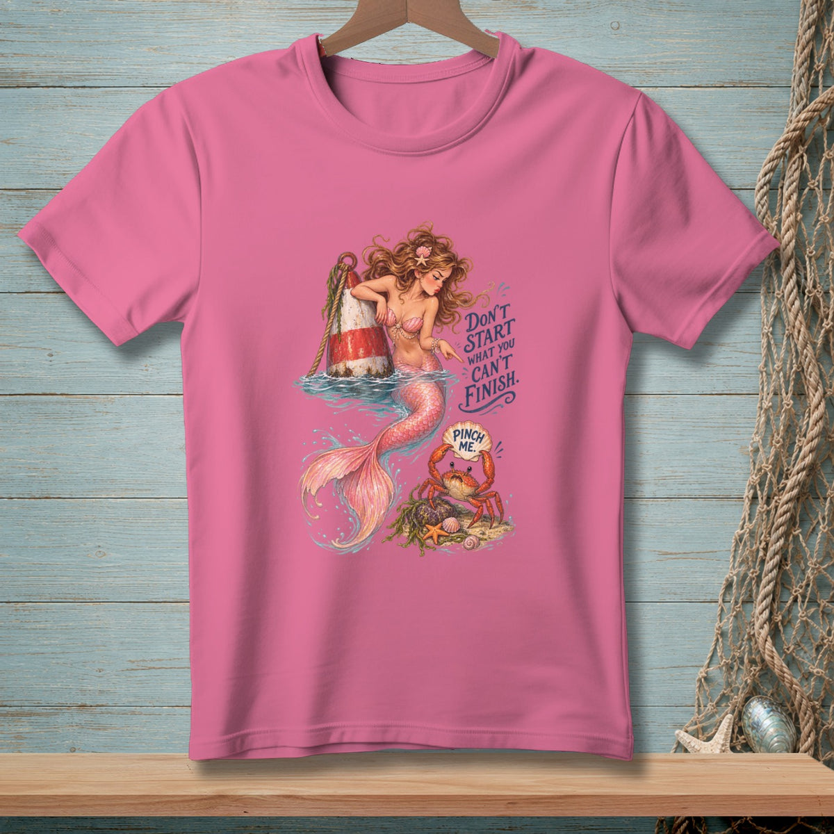 Pink t-shirt with a mermaid, buoy, crab, and text "Don't start what you can't finish. Pinch me."