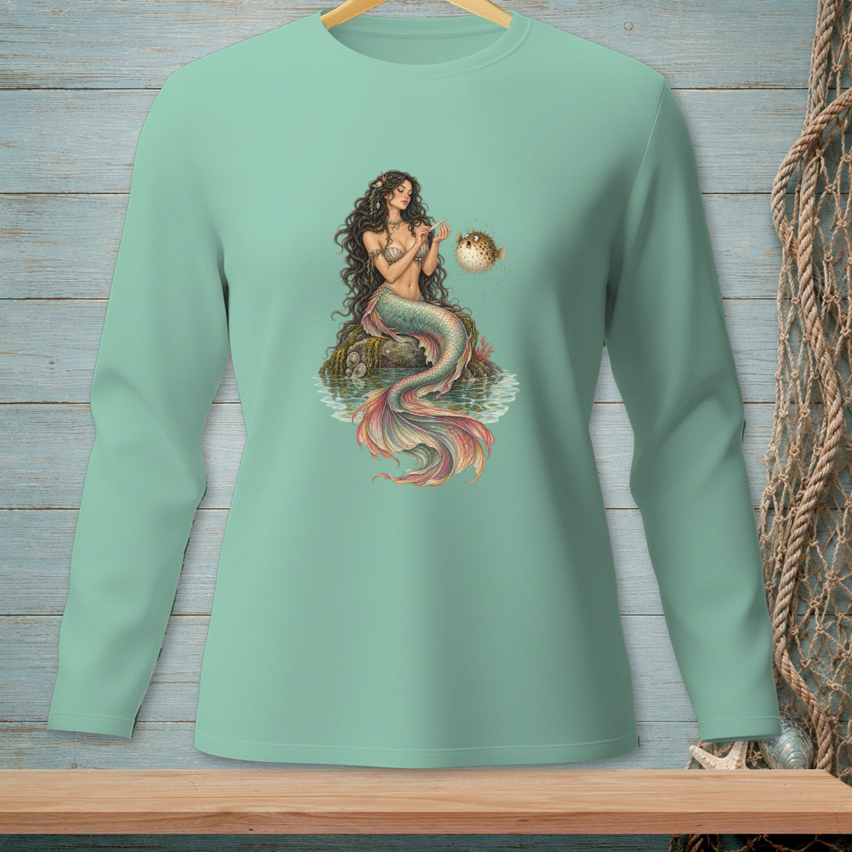 Mermaid sitting on rocks with colorful tail petting a pufferfish.