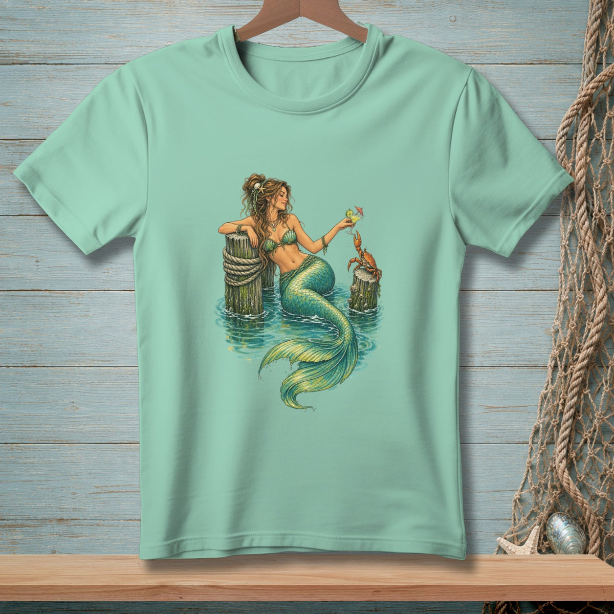 Mint t-shirt with illustration of a mermaid holding a drink and a crab on a post.