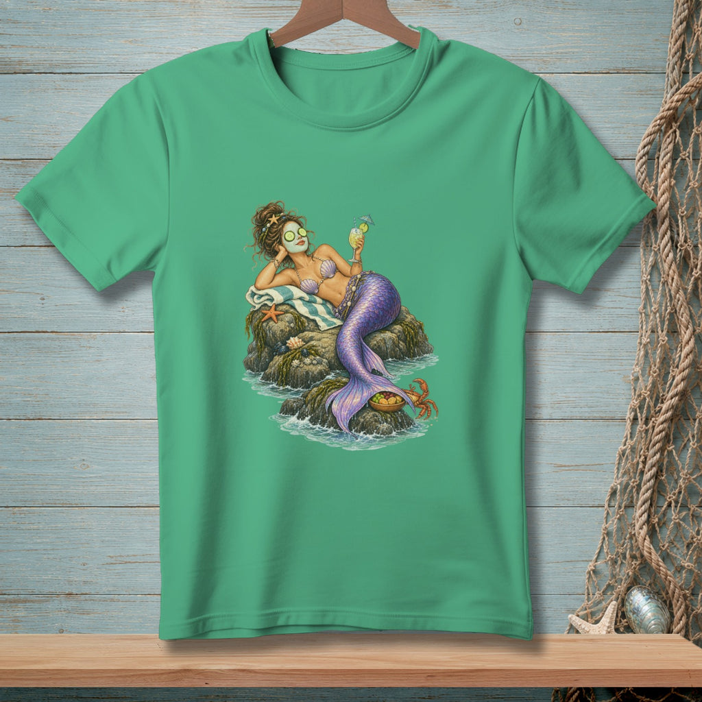 Green t-shirt with a mermaid relaxing on rocks, holding a drink.