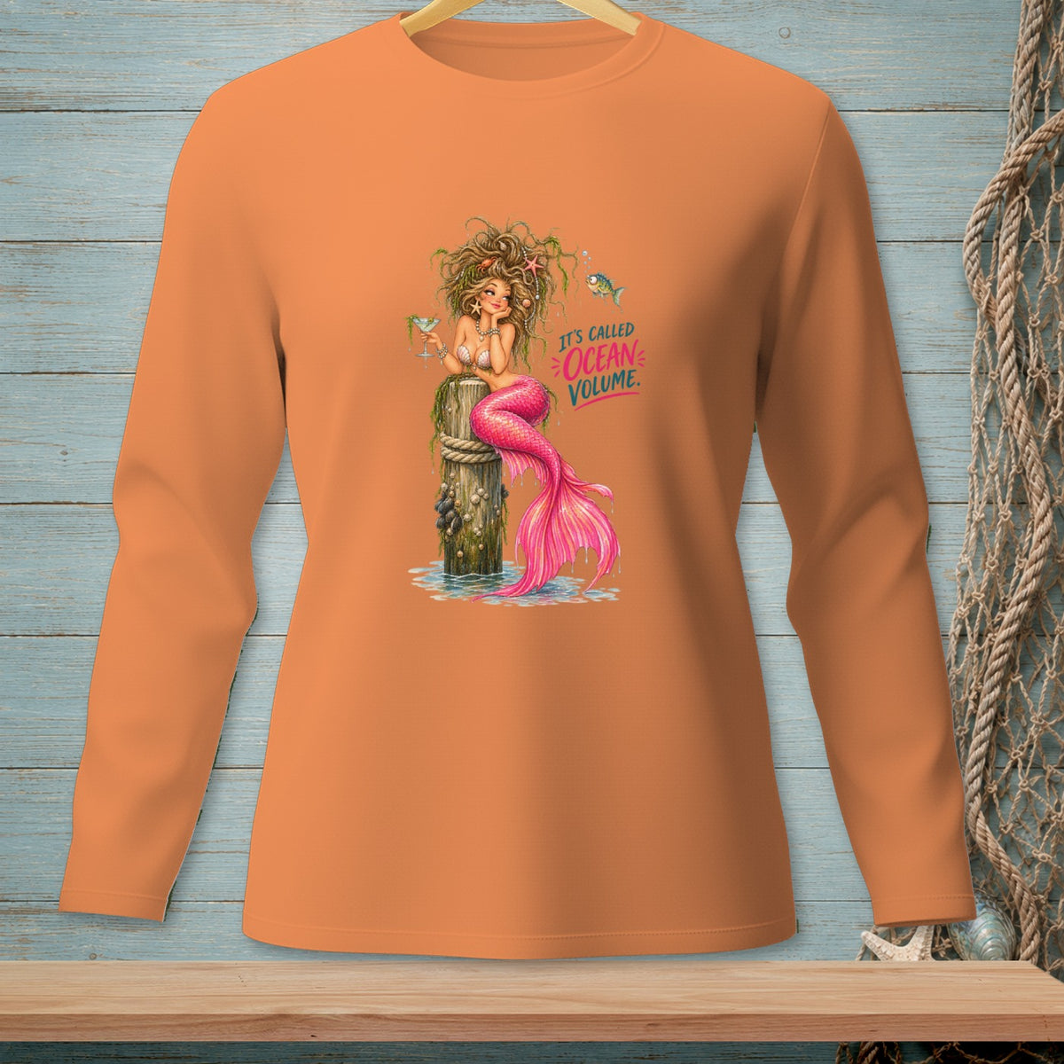 Orange long-sleeve shirt with a mermaid holding a drink and text "It's called ocean volume."