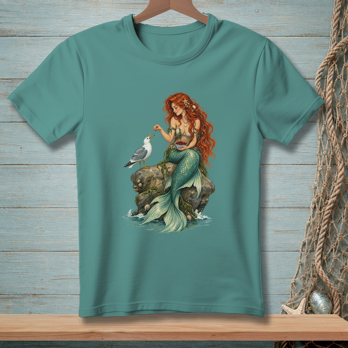 Mermaid with red hair feeding a seagull from a bowl of berries on a rock.