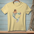 Pale yellow t-shirt with a watercolor illustration of a mermaid and a hand reaching for a bottle.