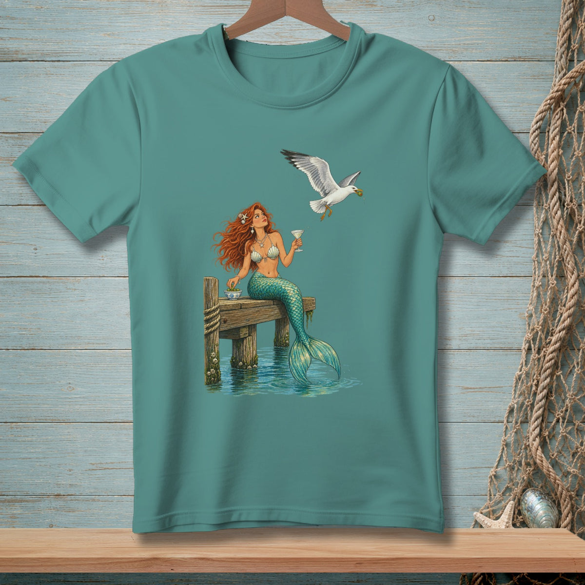 Mermaid sits on a pier with a cocktail, while a seagull flies by holding food.