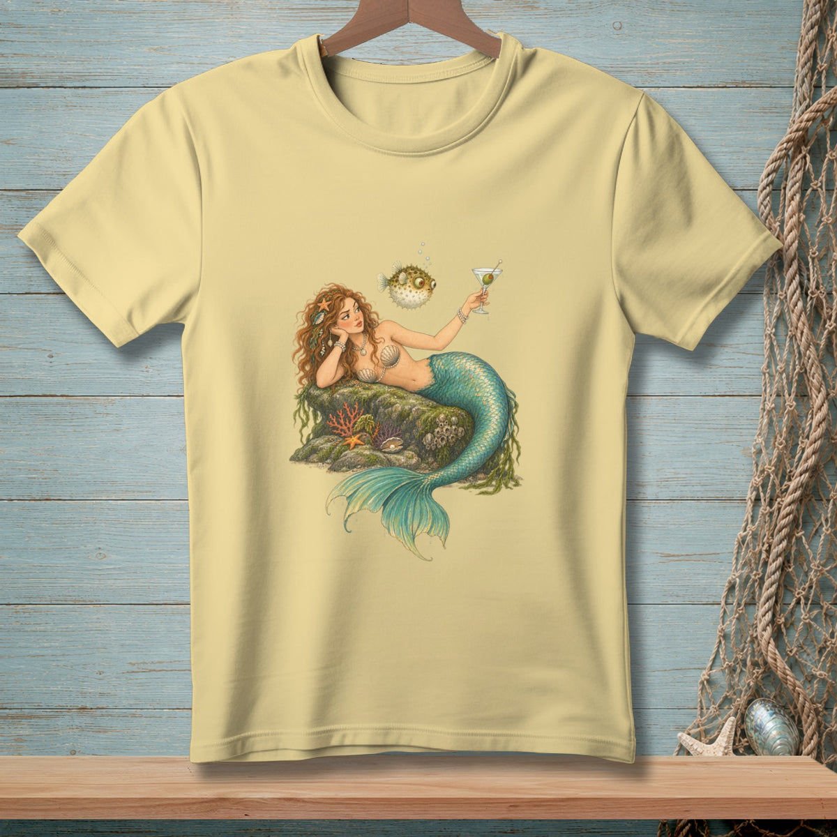 Light yellow t-shirt featuring a mermaid with a cocktail and a pufferfish.