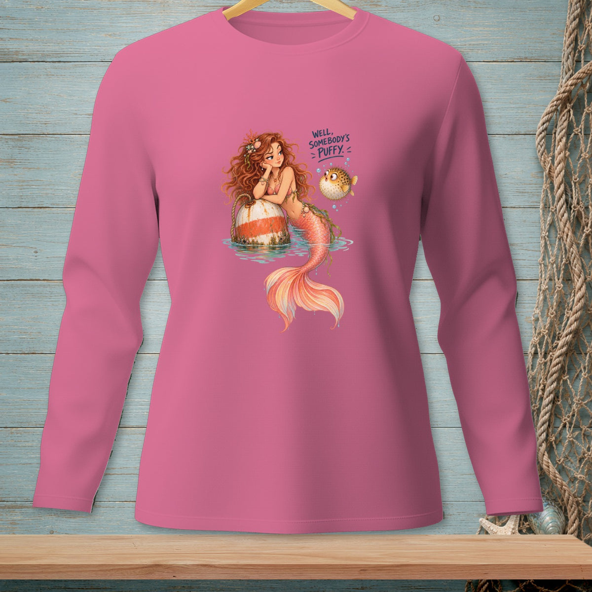 Pink long-sleeve shirt with mermaid illustration and text "Well, somebody's puffy."