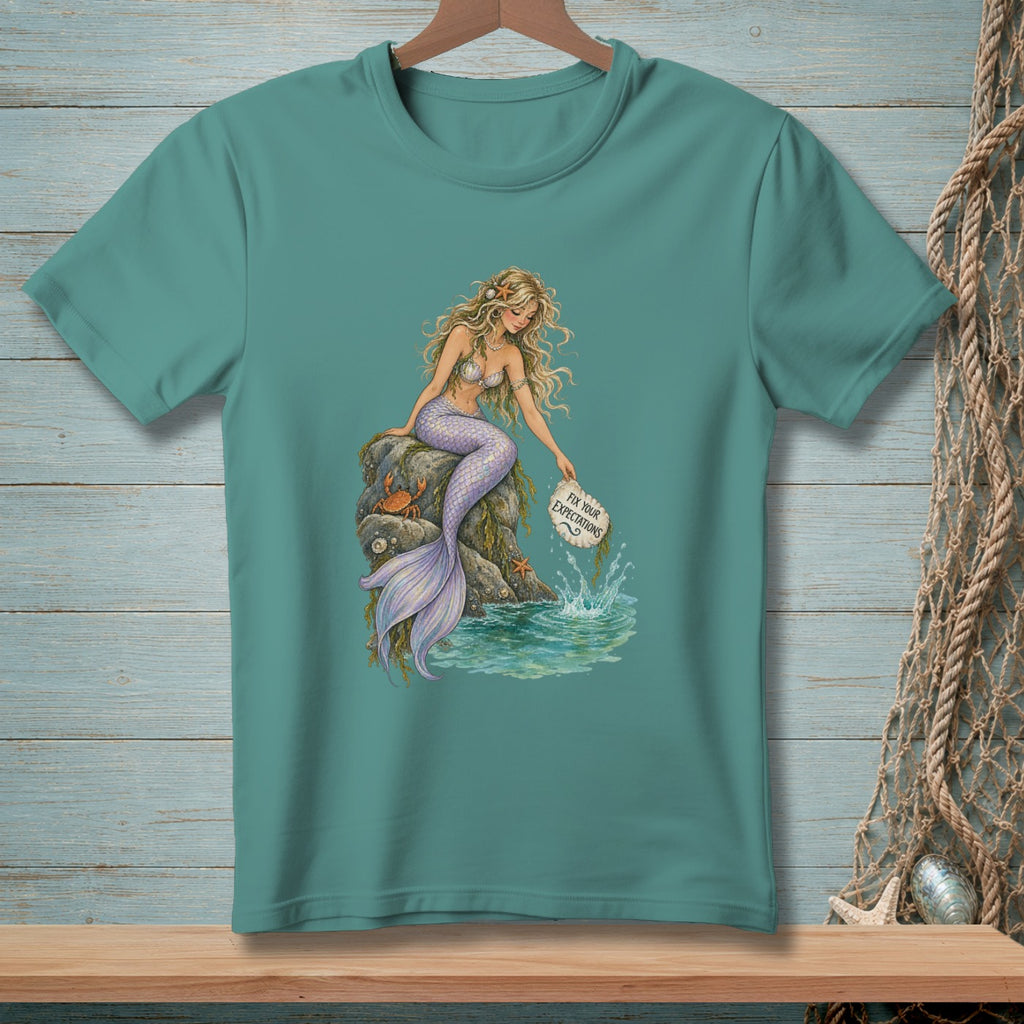 Mermaid sitting on a rock, holding sign that says "Fix Your Expectations".