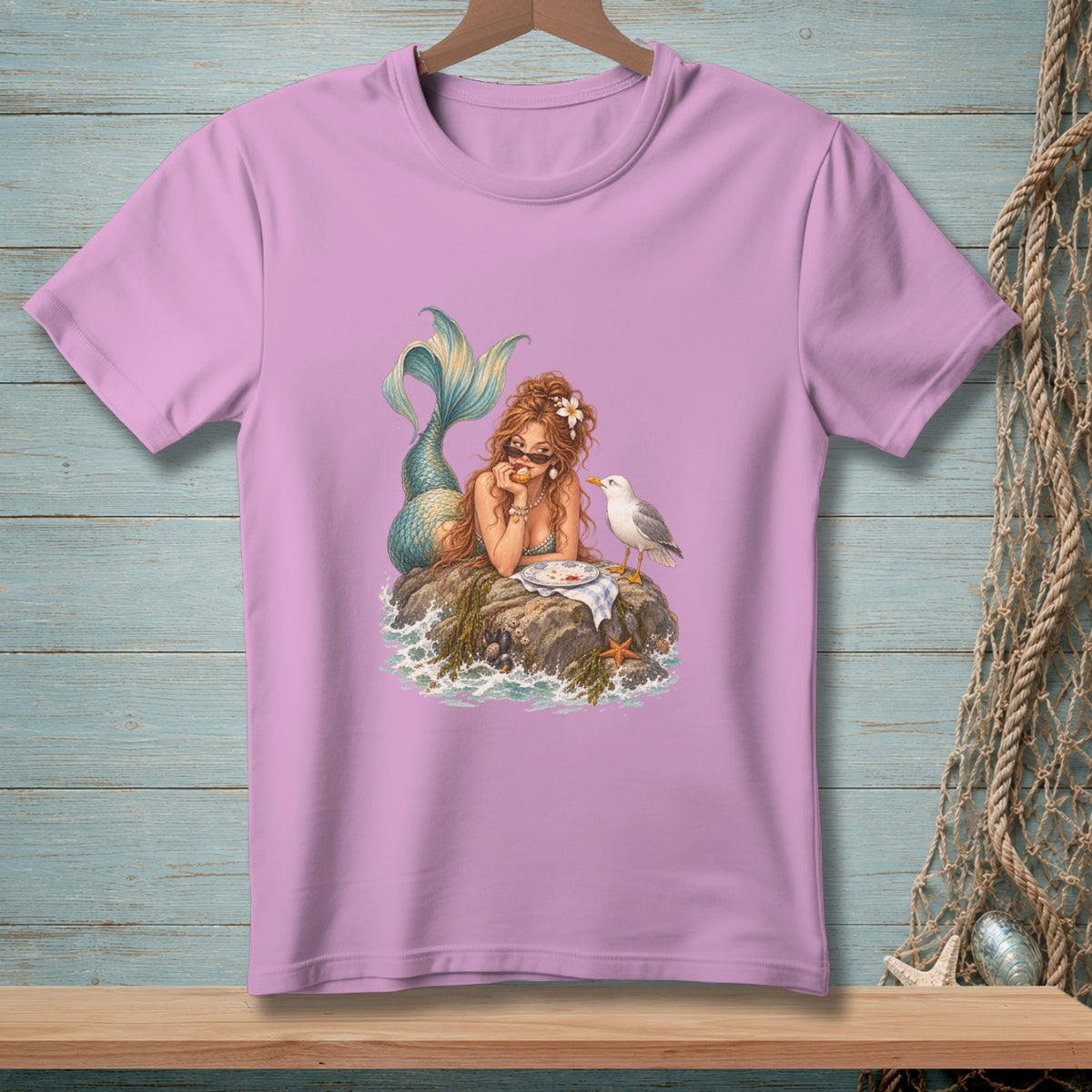 Pink t-shirt with a mermaid sitting on a rock with a seagull.