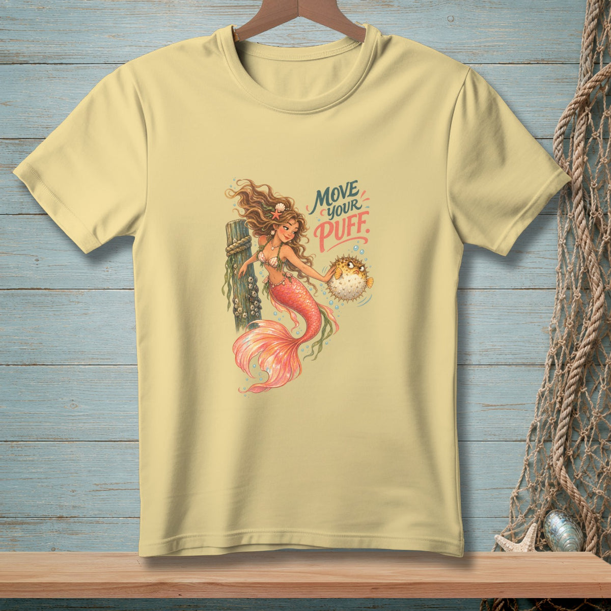 Light yellow t-shirt featuring a mermaid holding a pufferfish with text "Move Your Puff".