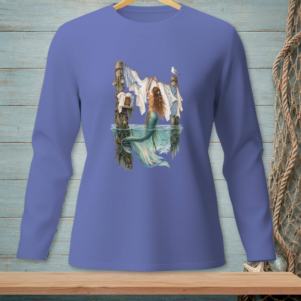 Long-sleeve shirt with a mermaid hanging laundry on a clothesline in the ocean.