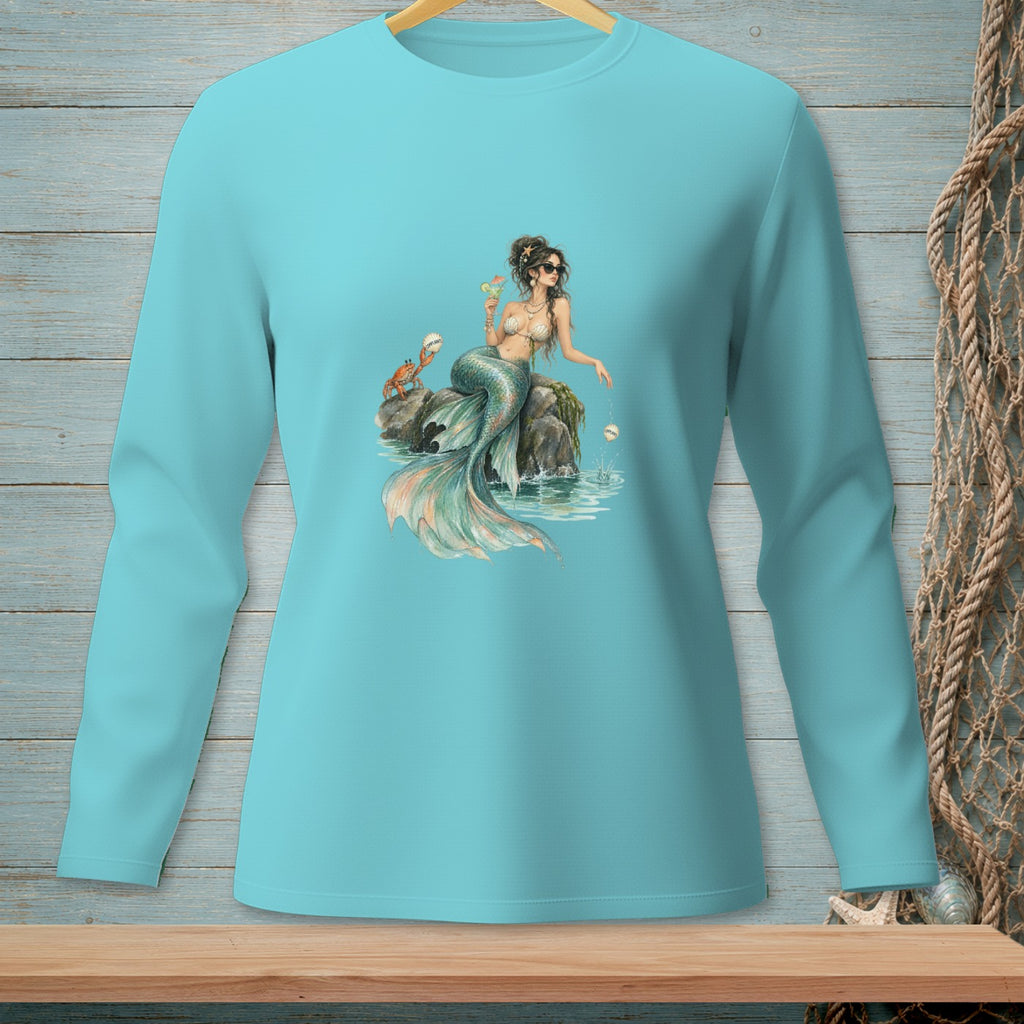 Teal long-sleeve shirt with a mermaid graphic holding a drink on a rock.