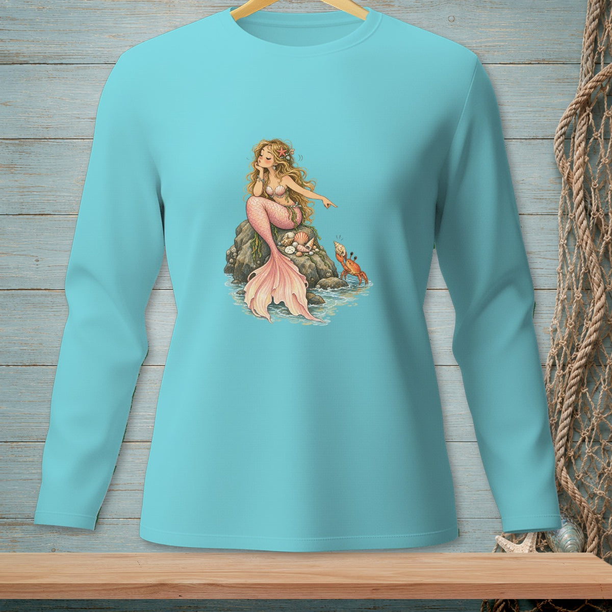 Long-sleeve teal shirt with a blonde mermaid pointing at a crab on a rock.