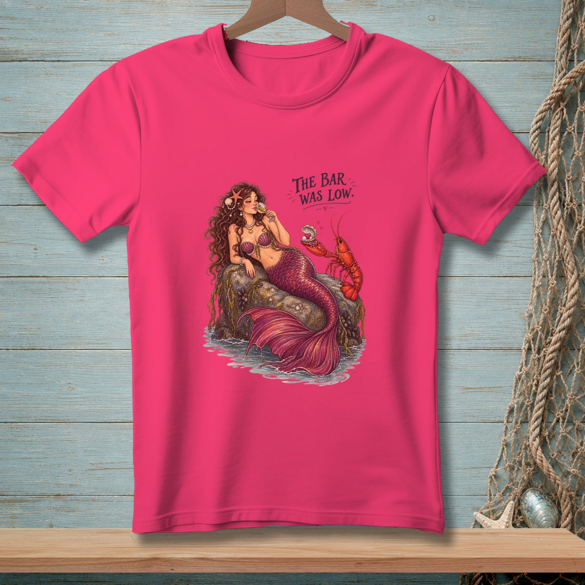 Mermaid with lobster on rock, drinking from glass. Text reads "The Bar Was Low."