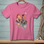 Pink t-shirt with two mermaids sitting on rocks with a seagull overhead.