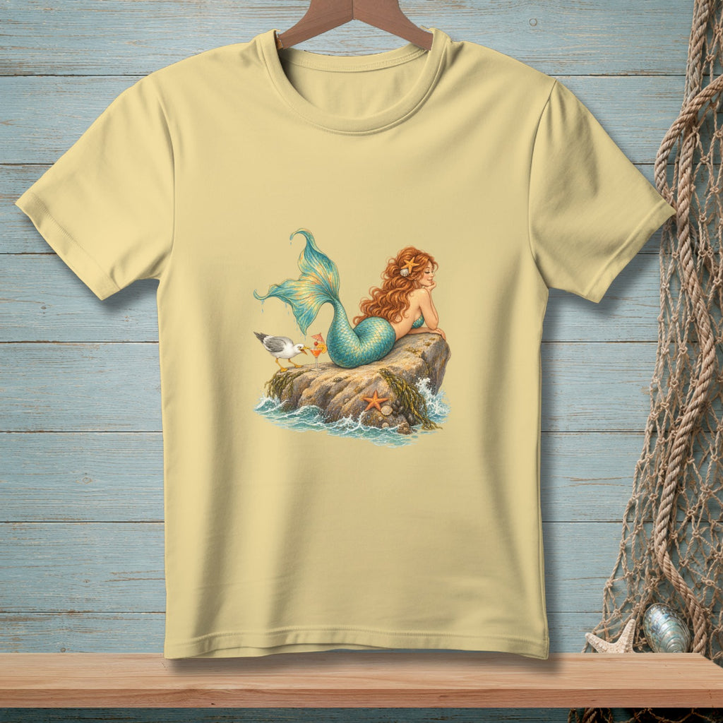 Light yellow t-shirt with a detailed illustration of a mermaid and a seagull on a rock.