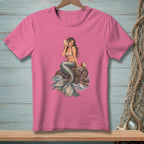 Pink t-shirt with an illustration of a mermaid sitting on a rock by the sea.