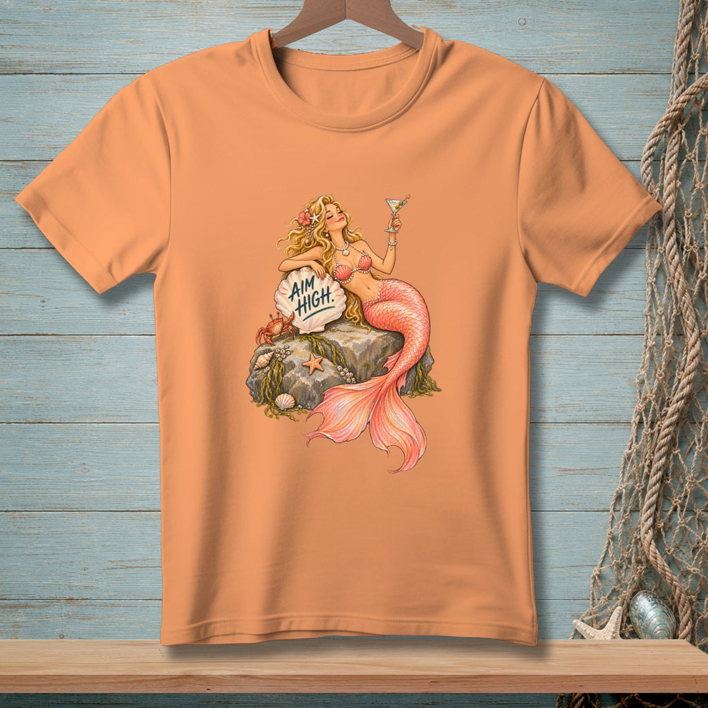 Peach t-shirt with a mermaid holding a martini and text that reads "Aim High."