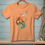 Mermaid with red hair and green tail feeding a seagull near a buoy.