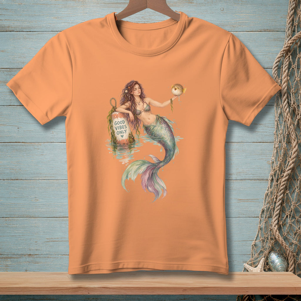 Orange t-shirt with a mermaid graphic holding a pufferfish and leaning on a buoy reading "GOOD VIBES ONLY".
