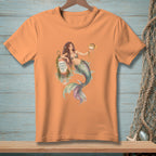 Orange t-shirt with a mermaid graphic holding a pufferfish and leaning on a buoy reading "GOOD VIBES ONLY".