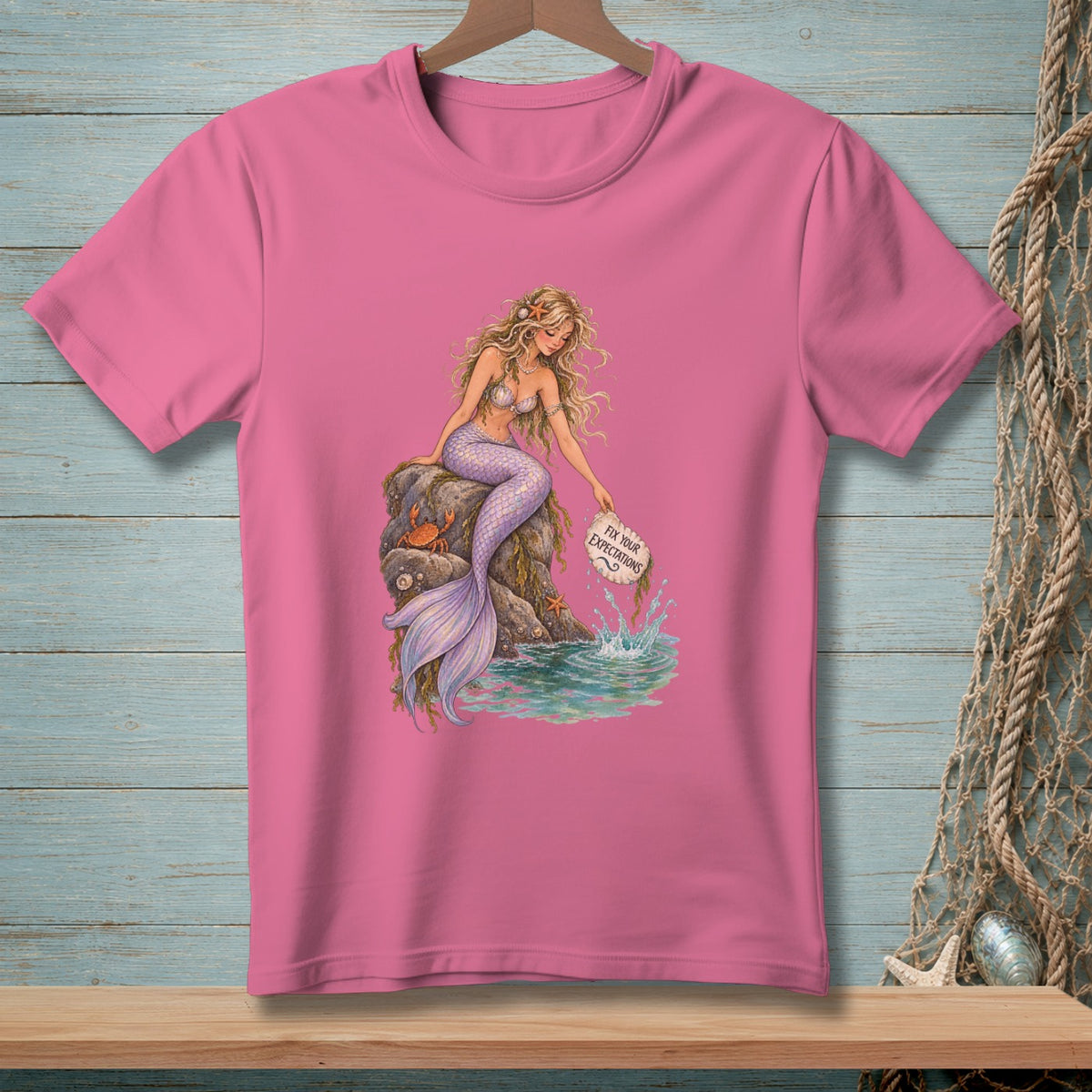 Mermaid sitting on rocks, holding a sign that says "Fix Your Expectations."